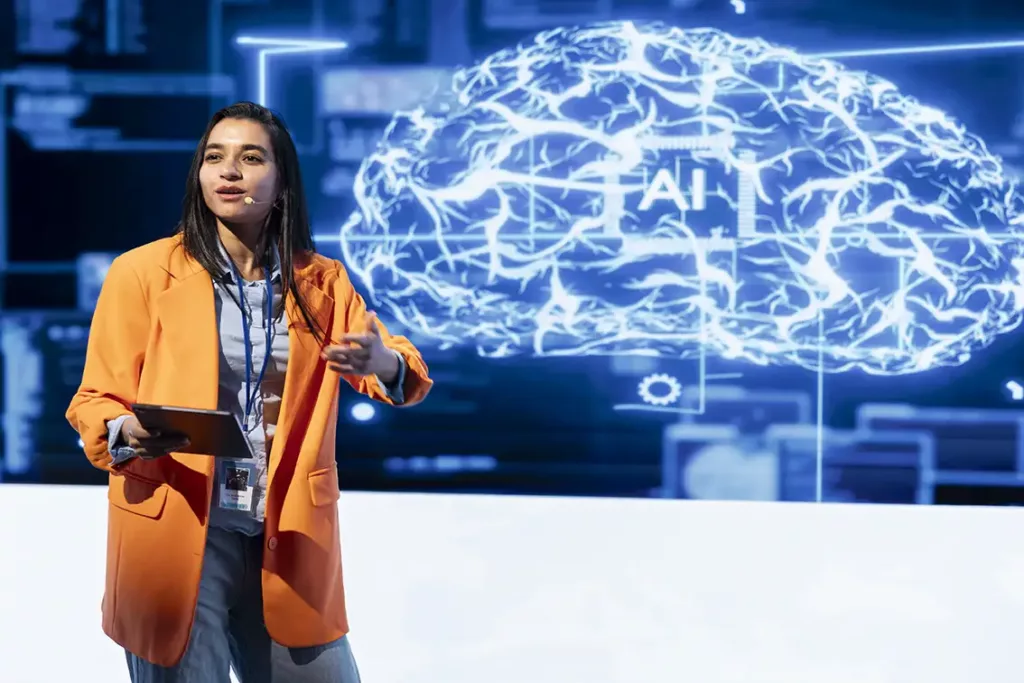 A lady making a presentation in front of a screen with an abstract AI image